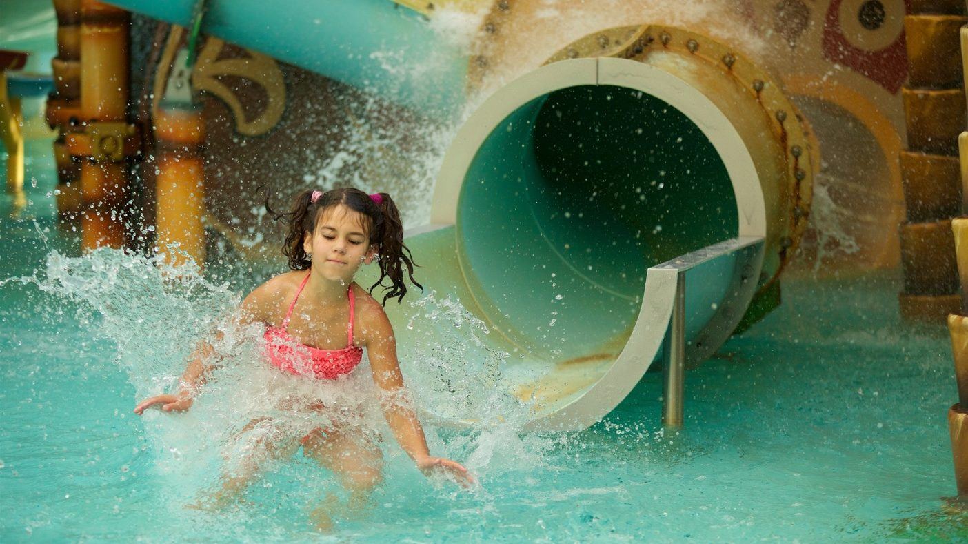 A girl emerging from a slide into the pool